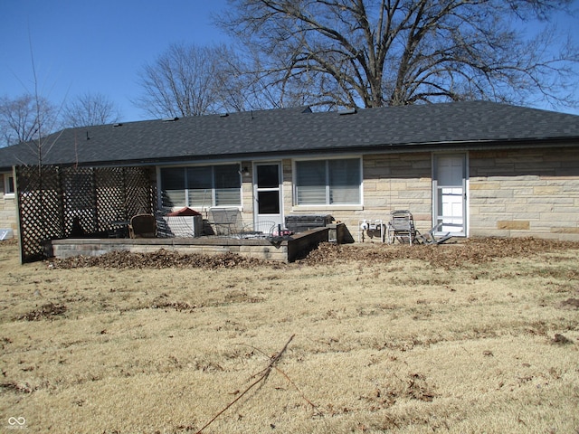 back of house with stone siding and a shingled roof