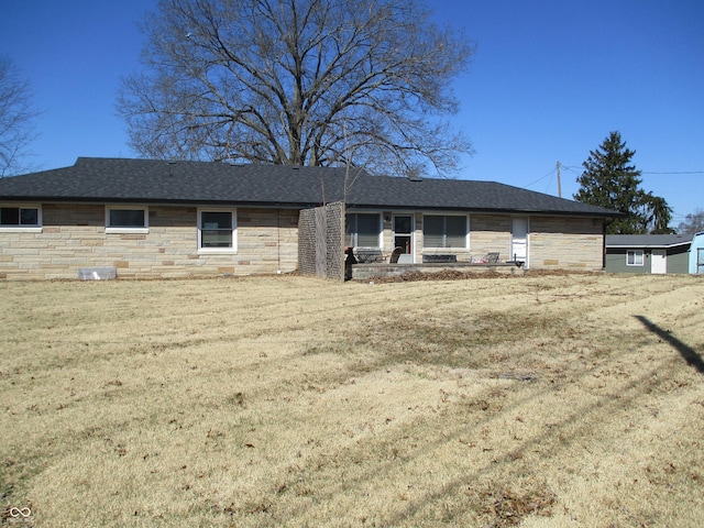 view of front of house featuring a front yard, stone siding, and roof with shingles