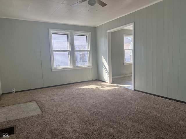 carpeted spare room with visible vents, baseboards, and a ceiling fan