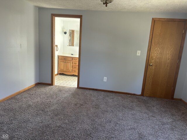 unfurnished room featuring light colored carpet, a textured ceiling, and baseboards