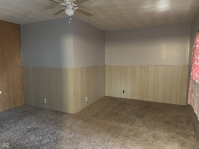 empty room featuring a wainscoted wall, wooden walls, and carpet floors