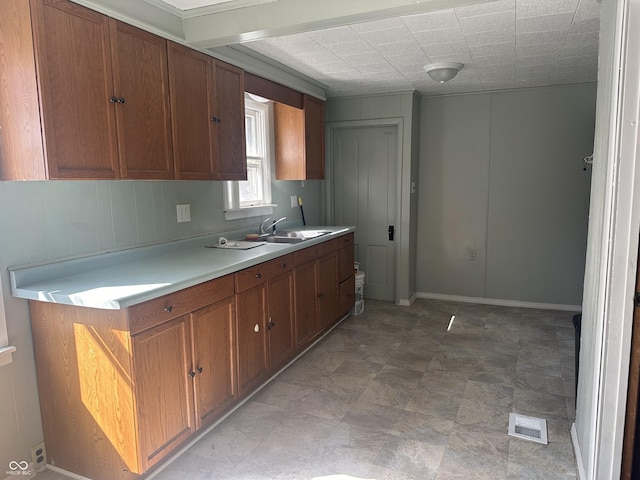 kitchen featuring visible vents, brown cabinets, light countertops, and a sink