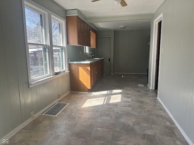 kitchen featuring a ceiling fan, brown cabinetry, visible vents, a sink, and light countertops