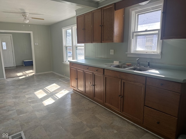 kitchen featuring a ceiling fan, baseboards, visible vents, a sink, and light countertops