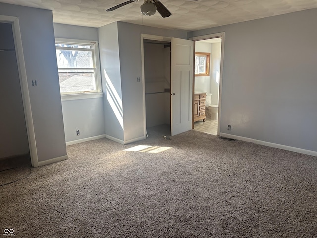 unfurnished bedroom with visible vents, a ceiling fan, connected bathroom, carpet flooring, and baseboards