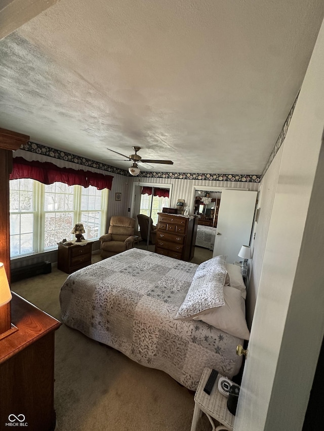 carpeted bedroom with a textured ceiling and a ceiling fan