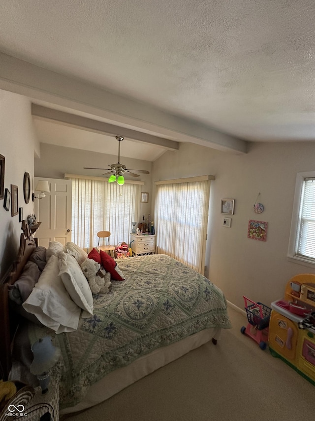 carpeted bedroom with a textured ceiling, lofted ceiling with beams, and a ceiling fan