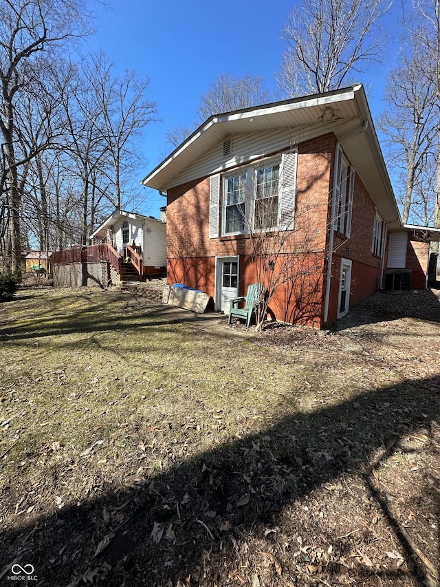 view of side of property featuring a yard, brick siding, and a wooden deck