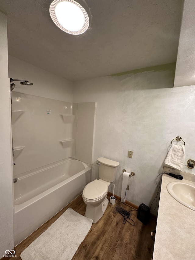 full bath with baseboards, toilet, bathtub / shower combination, wood finished floors, and a sink