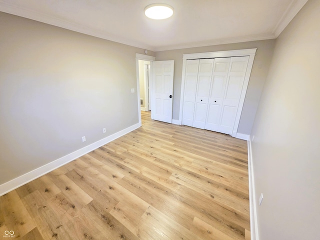 unfurnished bedroom featuring light wood-type flooring, baseboards, a closet, and crown molding