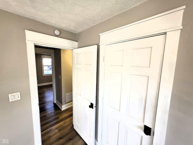 unfurnished bedroom featuring a closet, visible vents, dark wood-style flooring, and a textured ceiling