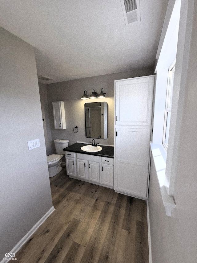 bathroom with visible vents, baseboards, toilet, wood finished floors, and vanity