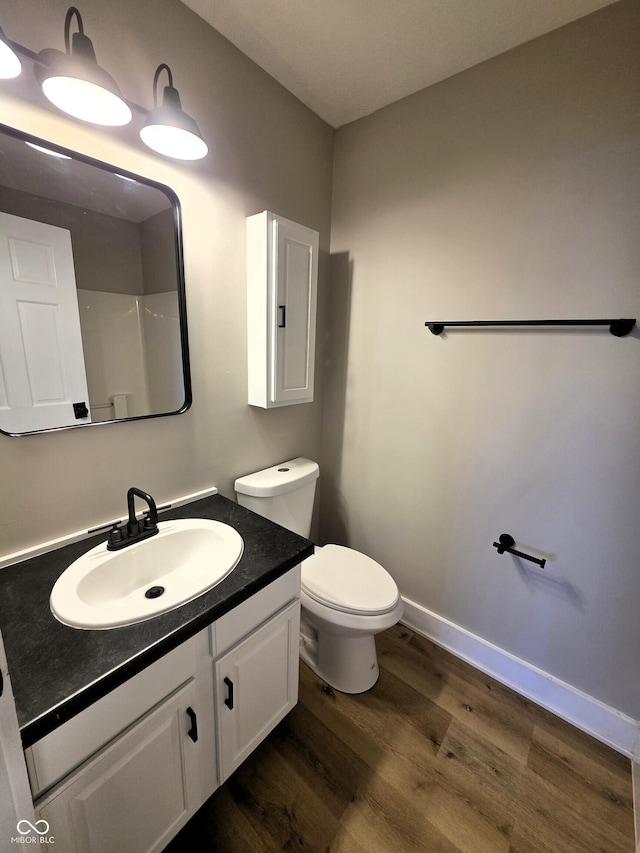 full bathroom featuring baseboards, toilet, wood finished floors, and vanity