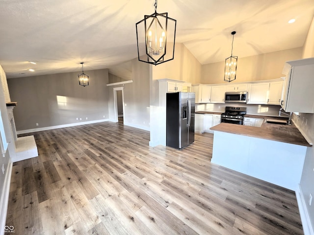 kitchen with light wood-style flooring, a sink, appliances with stainless steel finishes, open floor plan, and a chandelier