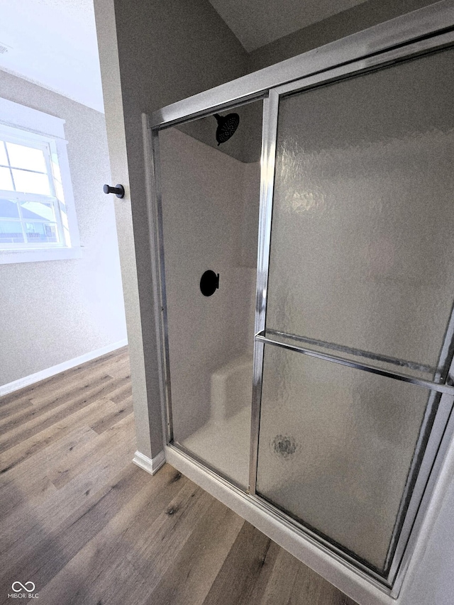 full bath with baseboards, wood finished floors, and a shower stall