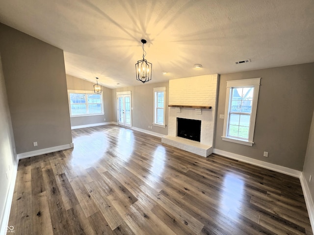 unfurnished living room featuring visible vents, baseboards, a fireplace, an inviting chandelier, and dark wood-style flooring