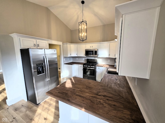 kitchen featuring high vaulted ceiling, appliances with stainless steel finishes, white cabinetry, and a peninsula