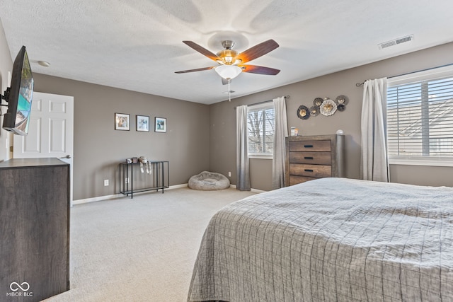 carpeted bedroom with visible vents, ceiling fan, a textured ceiling, and baseboards