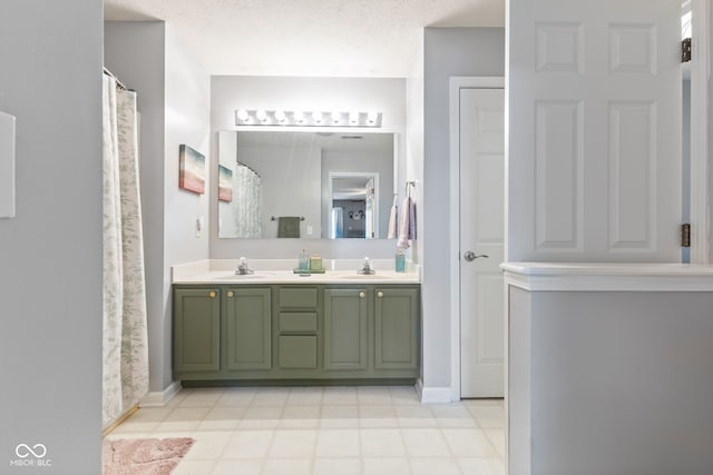 full bathroom featuring a textured ceiling, double vanity, baseboards, and a sink