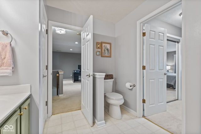 ensuite bathroom with vanity, toilet, ensuite bathroom, and a textured ceiling