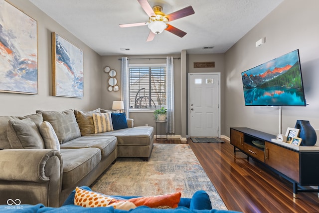 living room with dark wood-style floors, baseboards, visible vents, ceiling fan, and a textured ceiling