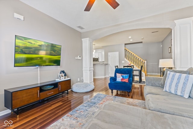 living area featuring stairs, decorative columns, wood finished floors, and a ceiling fan