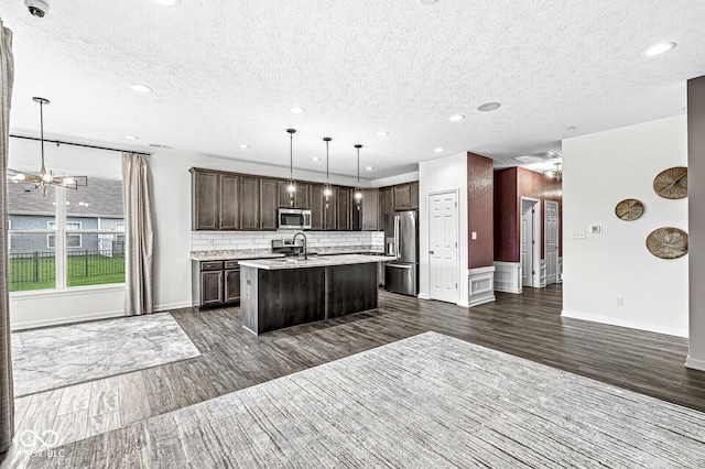 kitchen with stainless steel appliances, open floor plan, light countertops, and dark brown cabinetry