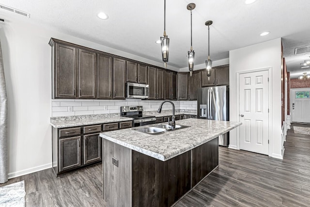 kitchen with dark wood-style floors, backsplash, appliances with stainless steel finishes, a sink, and dark brown cabinetry