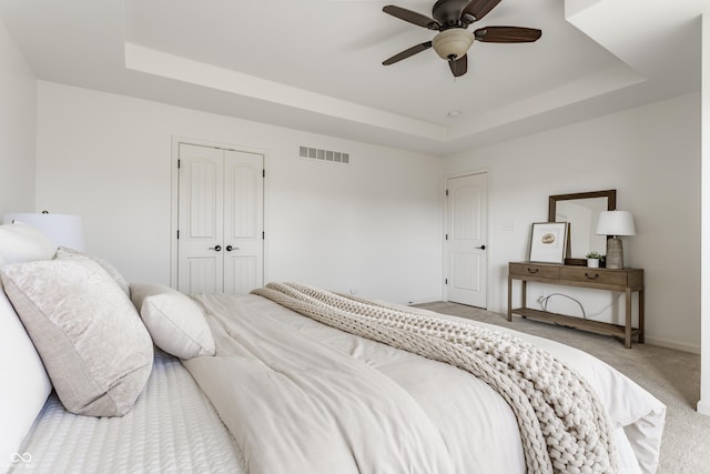 bedroom with a raised ceiling, carpet flooring, visible vents, and a closet