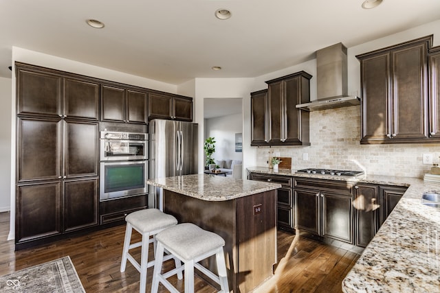 kitchen featuring decorative backsplash, dark wood-type flooring, a kitchen island, and wall chimney exhaust hood