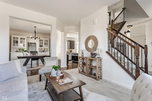 living room with baseboards, carpet, an inviting chandelier, and stairs