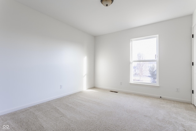 carpeted spare room with visible vents and baseboards