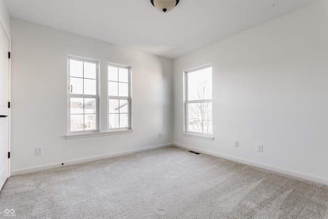 carpeted spare room featuring baseboards and visible vents