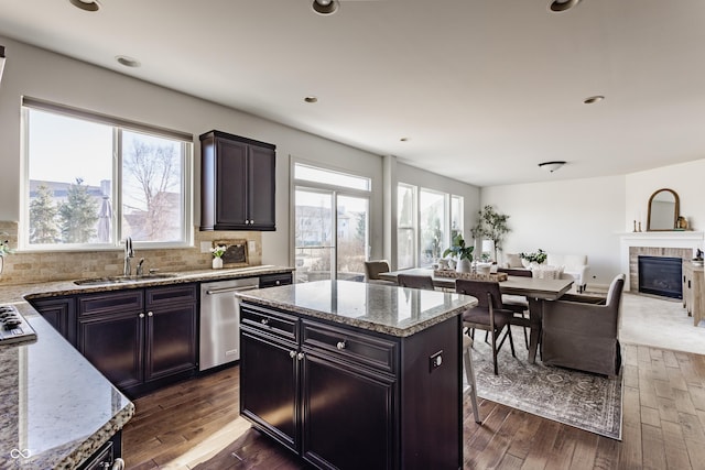 kitchen featuring a sink, tasteful backsplash, dark wood-style floors, stainless steel appliances, and a tile fireplace