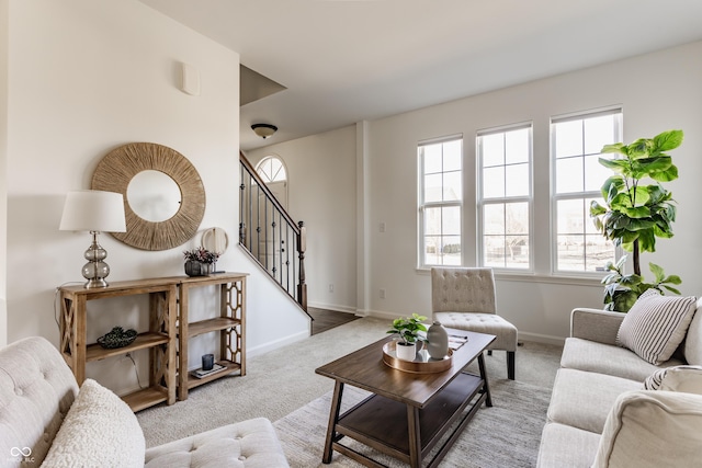 carpeted living area featuring stairway and baseboards