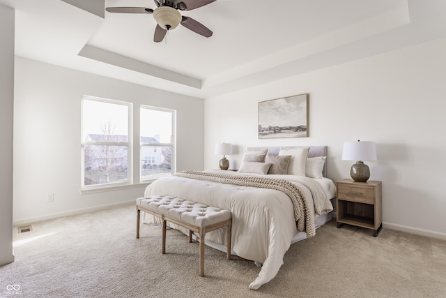 bedroom featuring visible vents, baseboards, carpet, and a tray ceiling