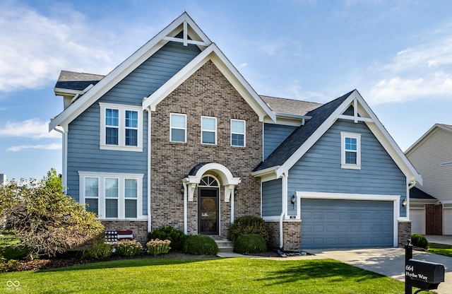 craftsman-style house with concrete driveway, a garage, brick siding, and a front yard