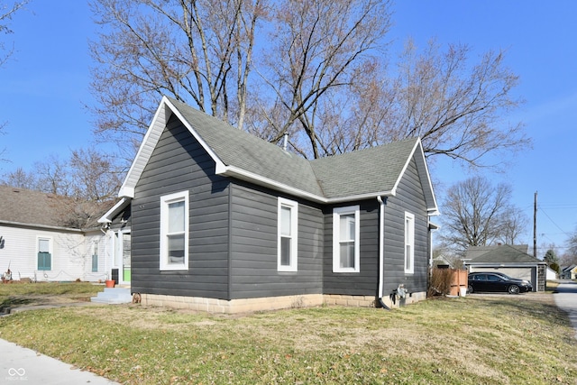 view of front facade featuring a shingled roof and a front lawn