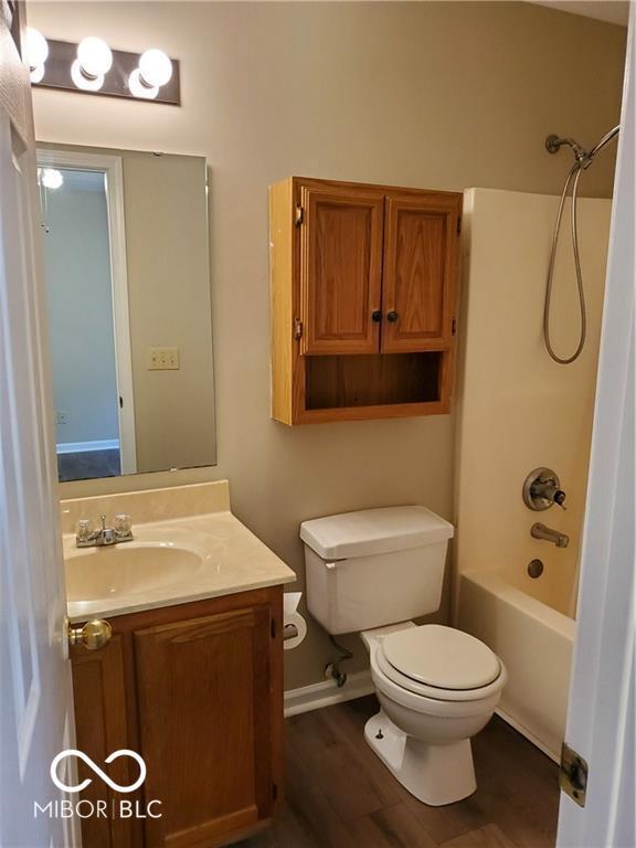 full bathroom with wood finished floors, shower / bath combination, vanity, and toilet