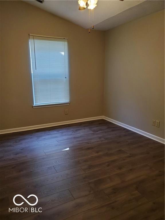 unfurnished room with vaulted ceiling, dark wood-type flooring, and baseboards