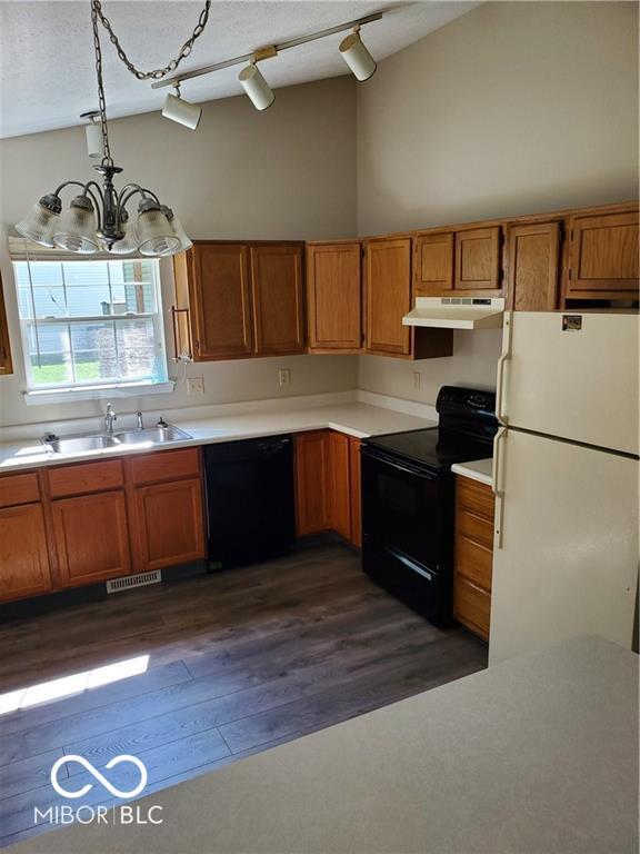 kitchen with black appliances, under cabinet range hood, light countertops, and a sink