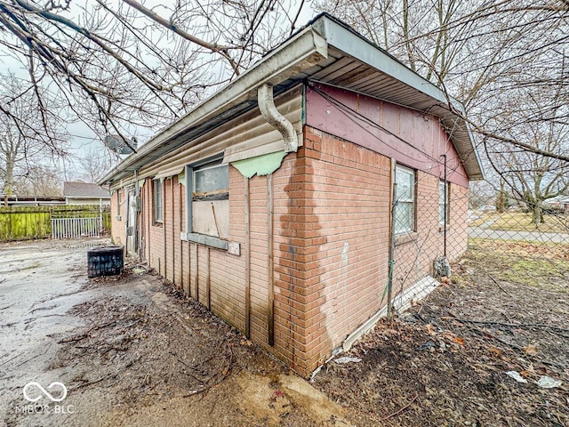 view of property exterior featuring brick siding and fence