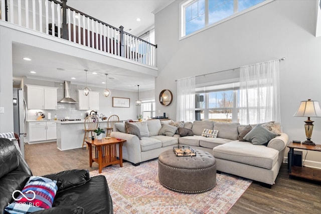 living room with recessed lighting, wood finished floors, and a towering ceiling