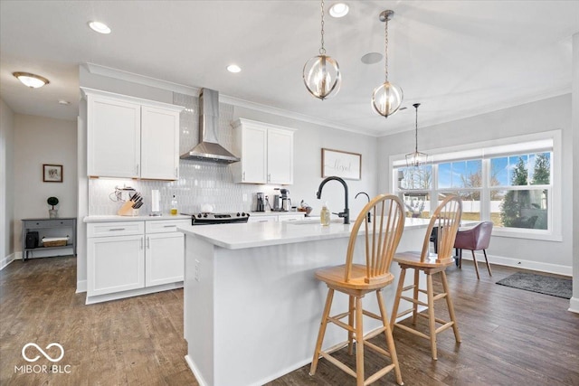 kitchen with dark wood finished floors, light countertops, decorative backsplash, wall chimney exhaust hood, and a sink