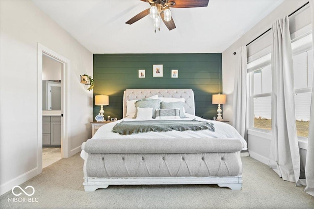 carpeted bedroom with connected bathroom, baseboards, wooden walls, and an accent wall