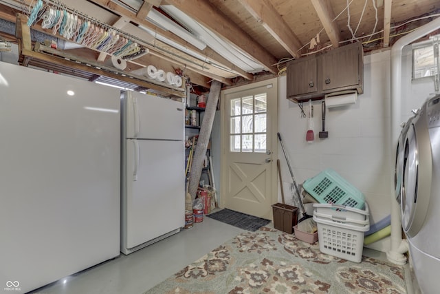 below grade area with concrete block wall, separate washer and dryer, and freestanding refrigerator