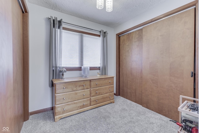 carpeted bedroom featuring baseboards, a closet, and a textured ceiling