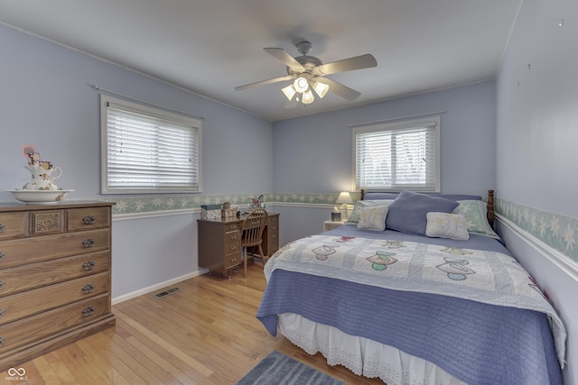 bedroom featuring light wood-type flooring, baseboards, visible vents, and ceiling fan