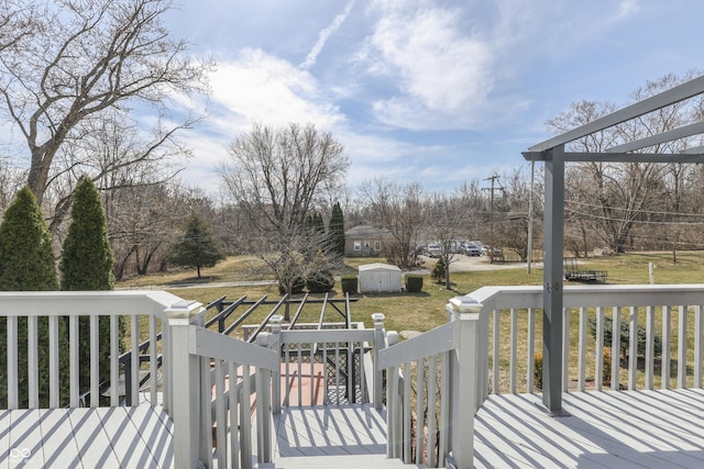 wooden terrace with a storage unit, a lawn, and an outdoor structure