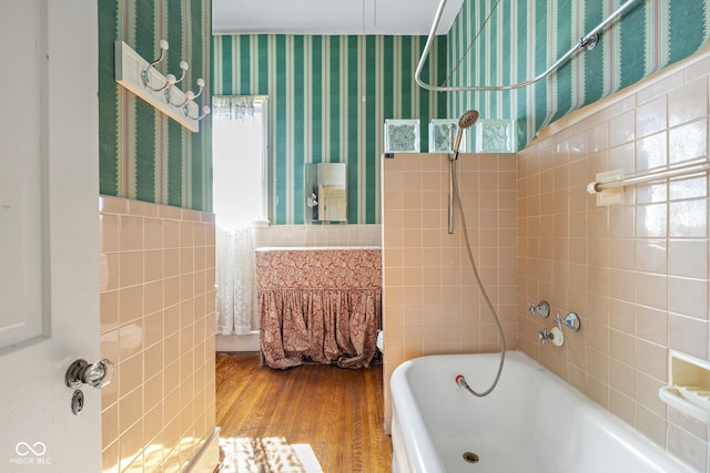 bathroom with tile walls, wood finished floors, wainscoting, and wallpapered walls